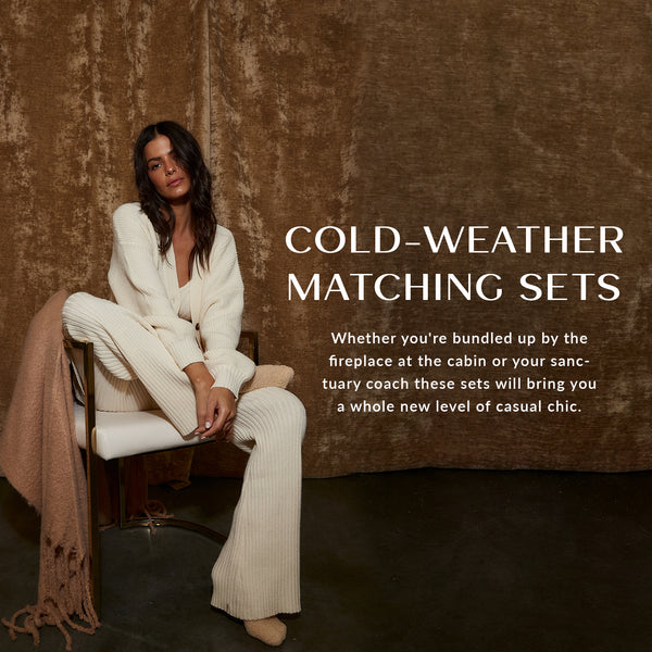 Cold-weather matching sets banner: woman in a cream ribbed knit lounge set on a chair.