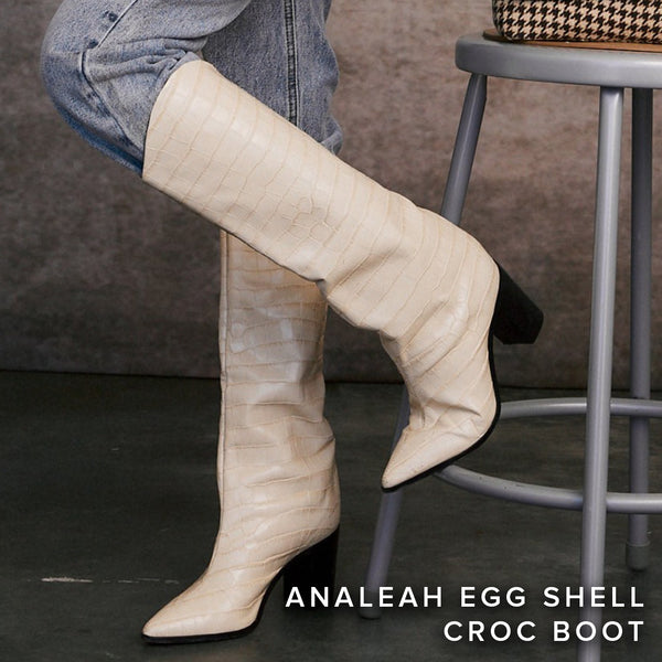 Egg shell croc-embossed knee-high Analeah boots styled with cropped jeans beside a stool.