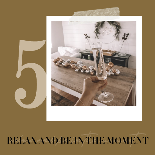 Self-care tip five, relax and be in the moment: hand raising champagne in a holiday-decorated room.