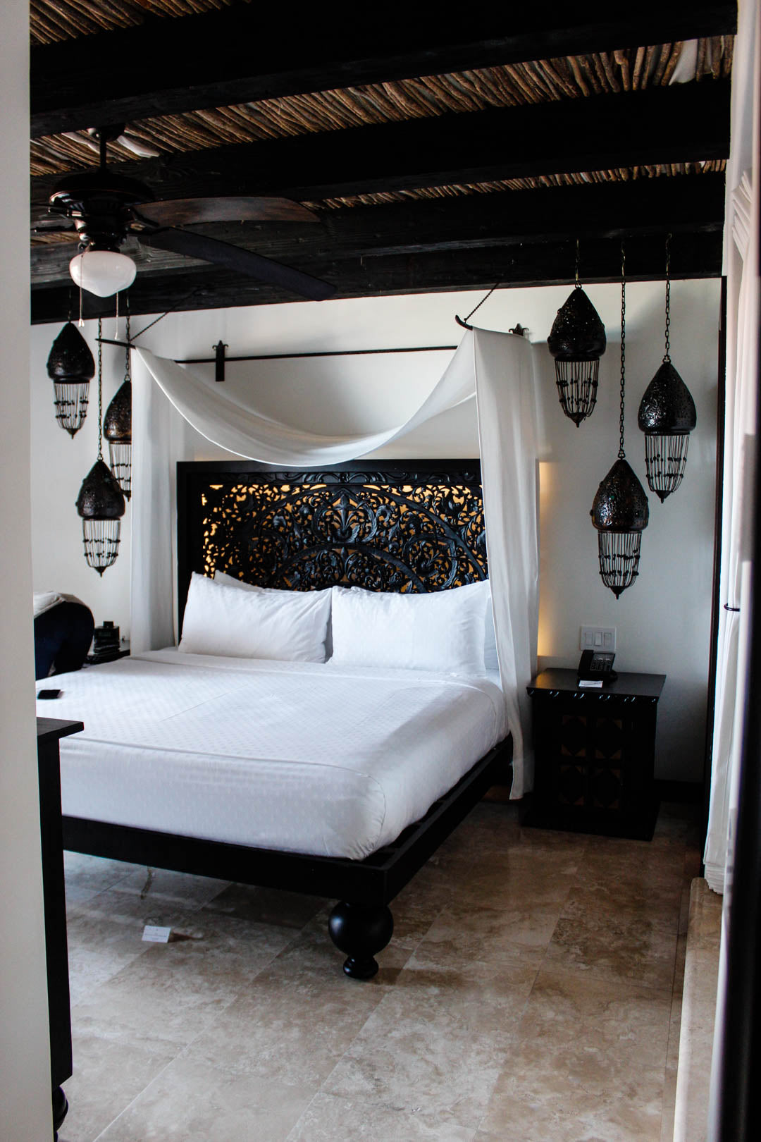 Carved black canopy bed and Moroccan lanterns in a Cabo San Lucas resort suite.