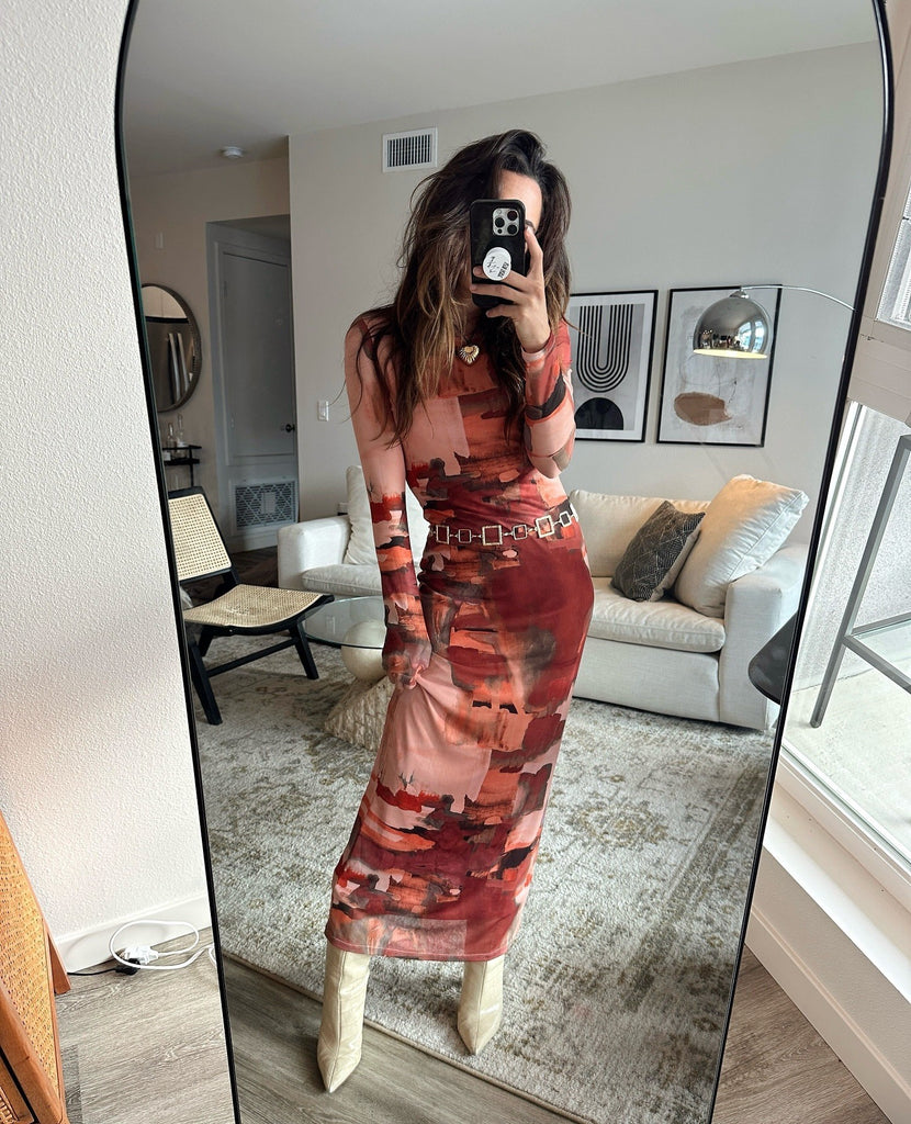 Mirror selfie in a rust abstract-print maxi dress paired with cream heeled boots.